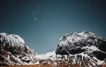 a snow covered mountain range under a night sky